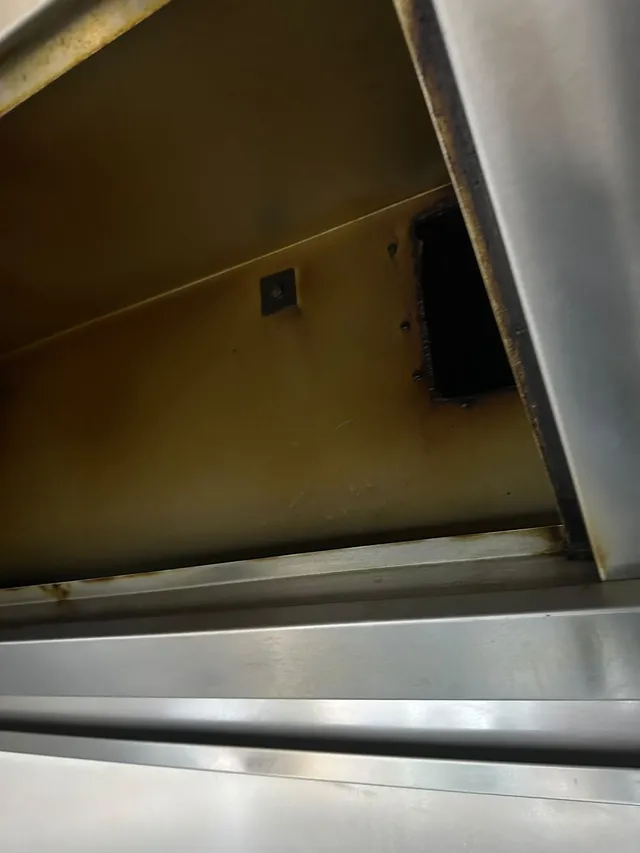 Inside a hood before cleaning, with yellow grease on the steel