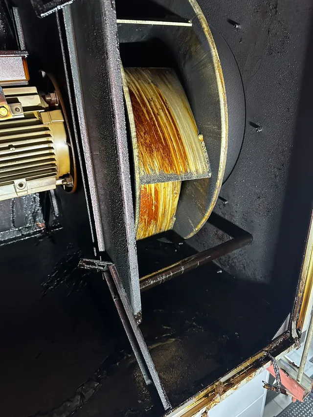 Inside a fan housing before cleaning, with grease on the wheel and casing